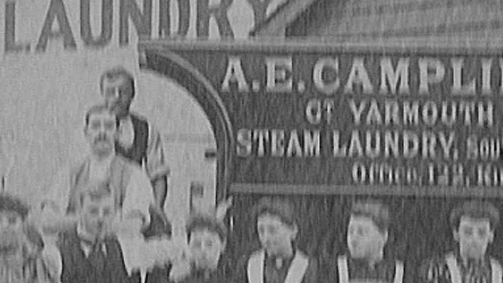 A group of people standing in front of a steam laundry.