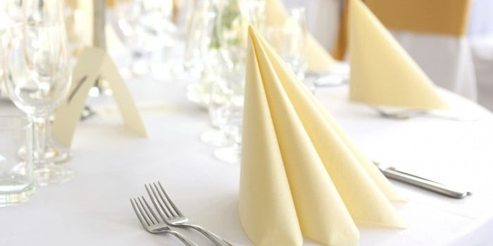 A table set with yellow napkins and silverware.