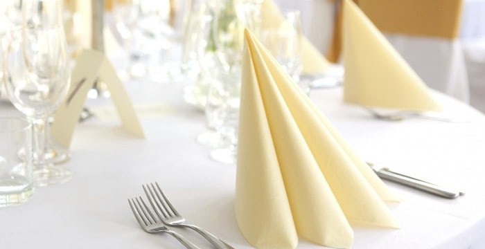 A table set with yellow napkins and silverware.