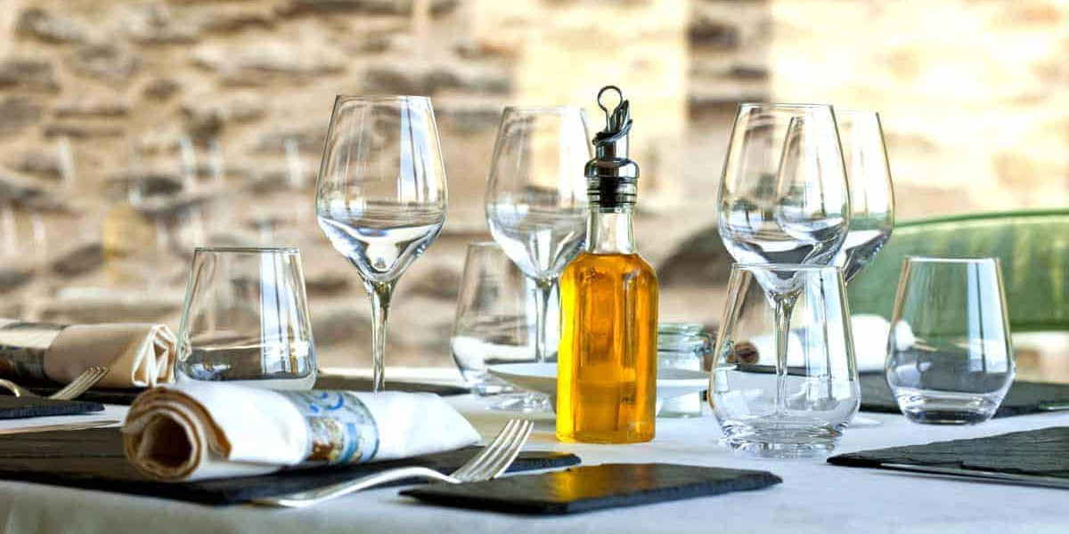 A table set with wine glasses and a bottle of olive oil.