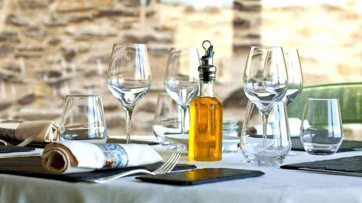 A table set with wine glasses and a bottle of olive oil.