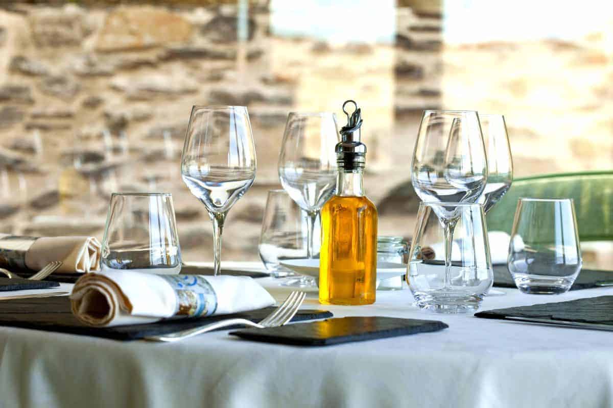 A table set with wine glasses and a bottle of olive oil.