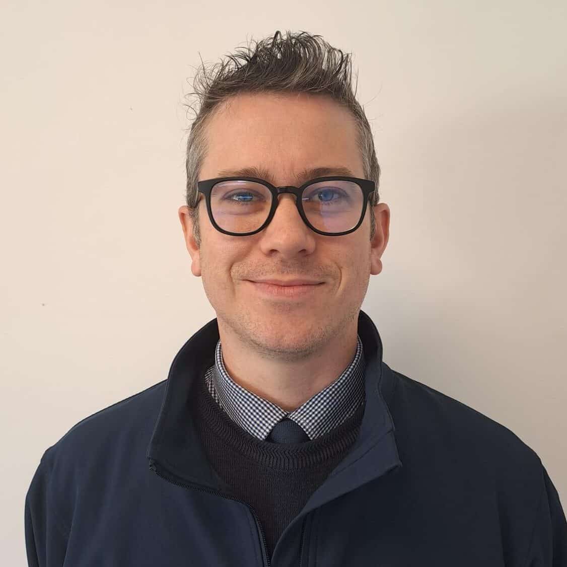A man wearing glasses and a blue jacket.