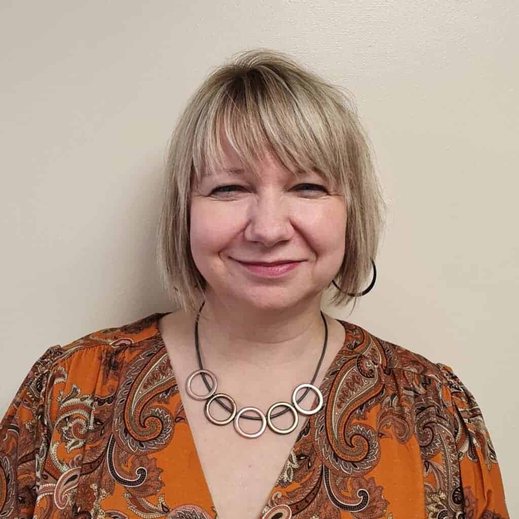 A woman in a paisley dress smiling at the camera.