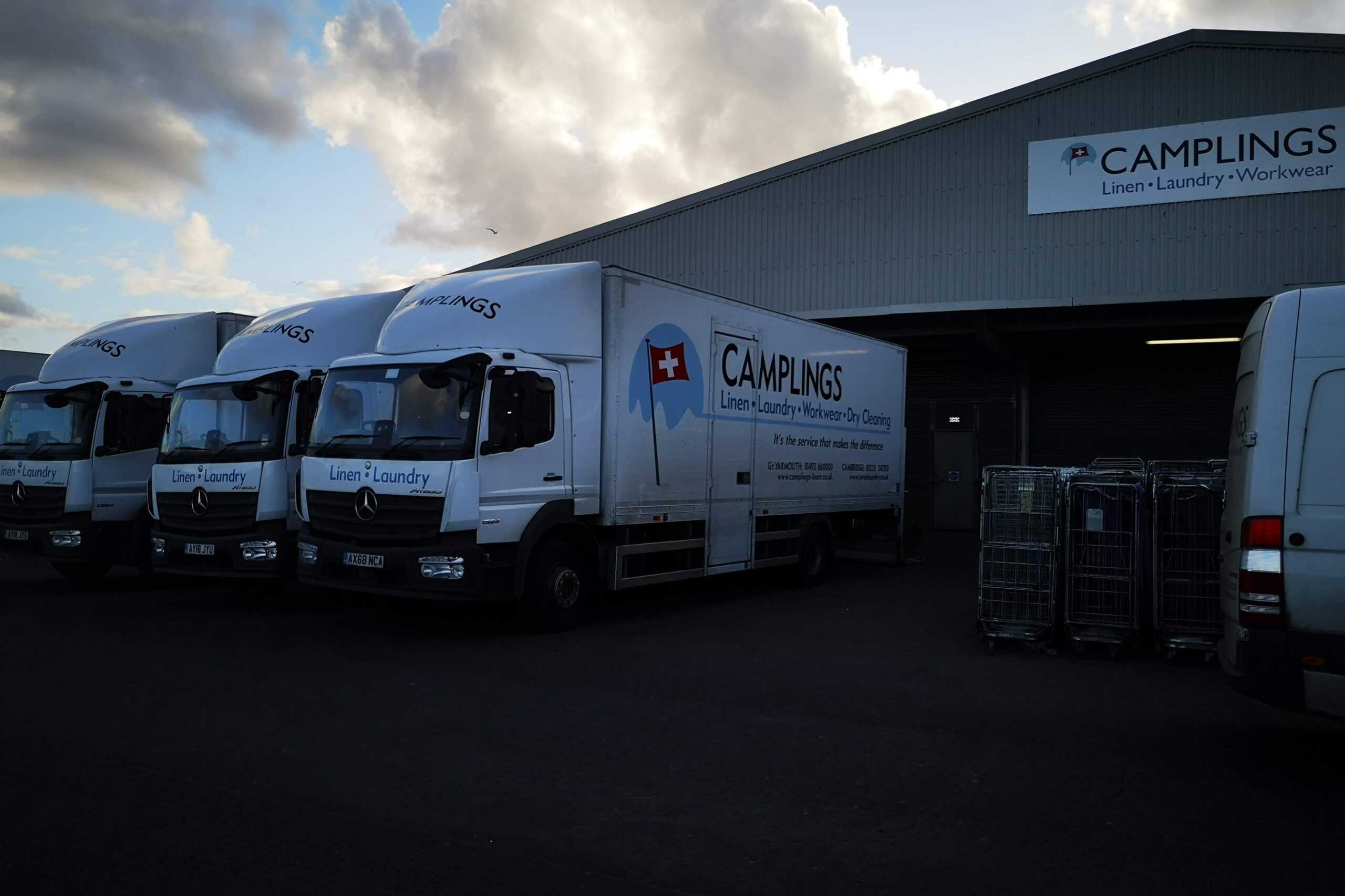 Three white trucks parked in front of a building.