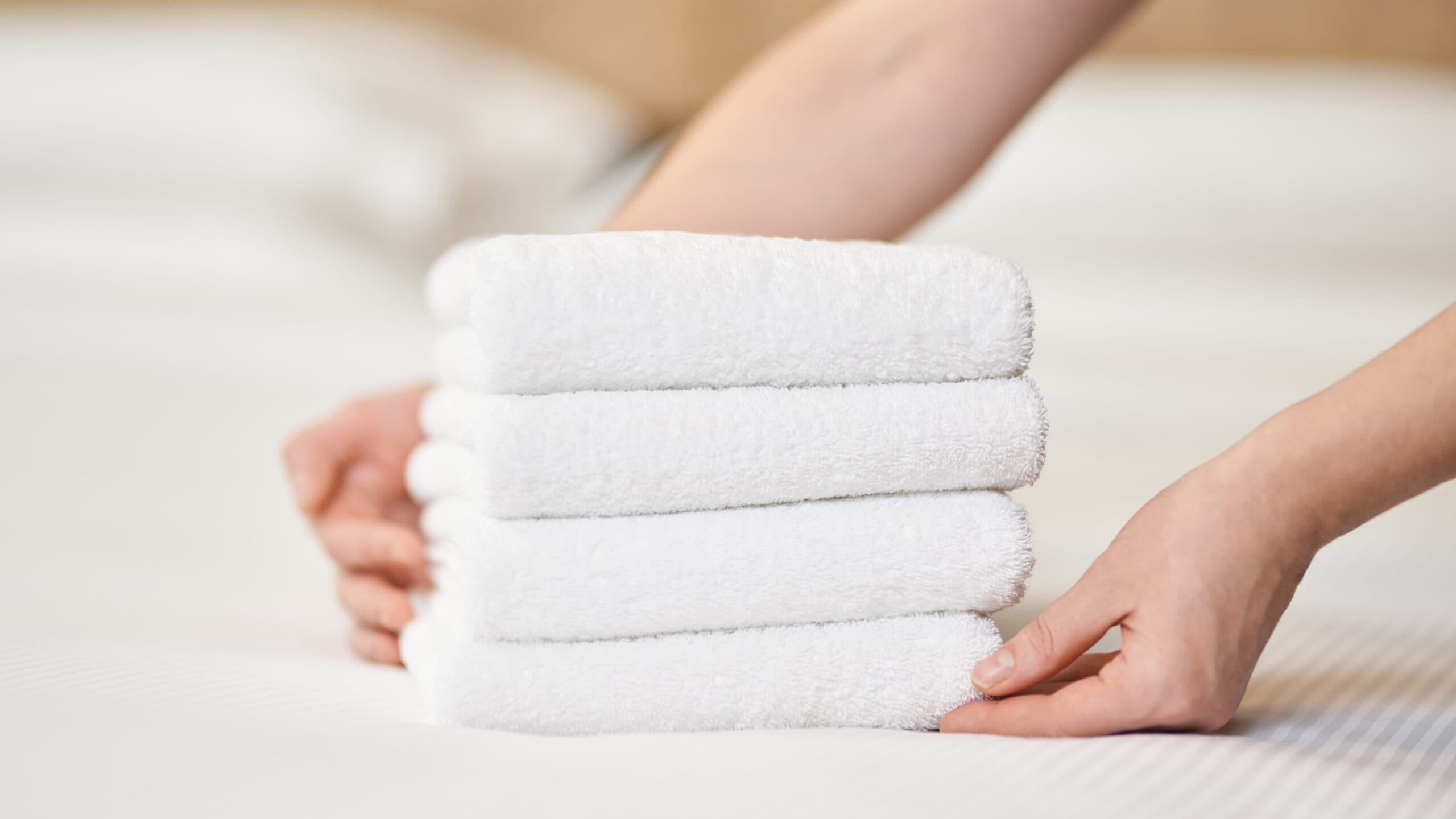 A stack of white towels on a bed.