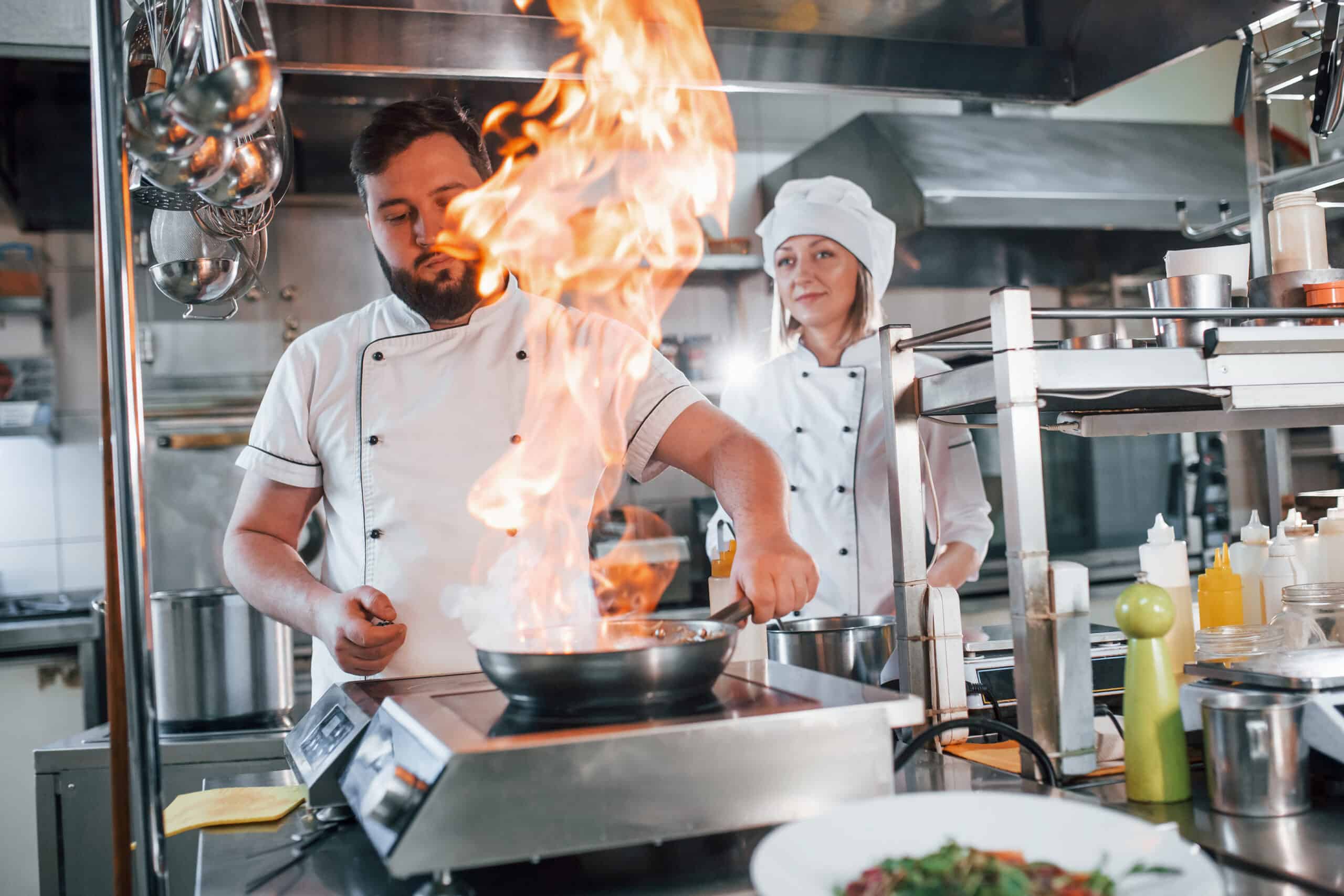 Flames in the frying pan. Professional chef preparing food in the kitchen