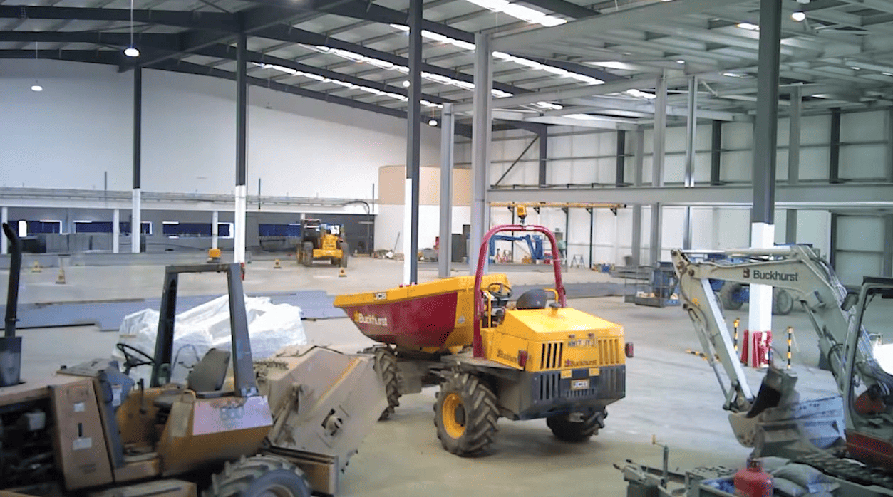 A yellow dump truck is parked in a warehouse.
